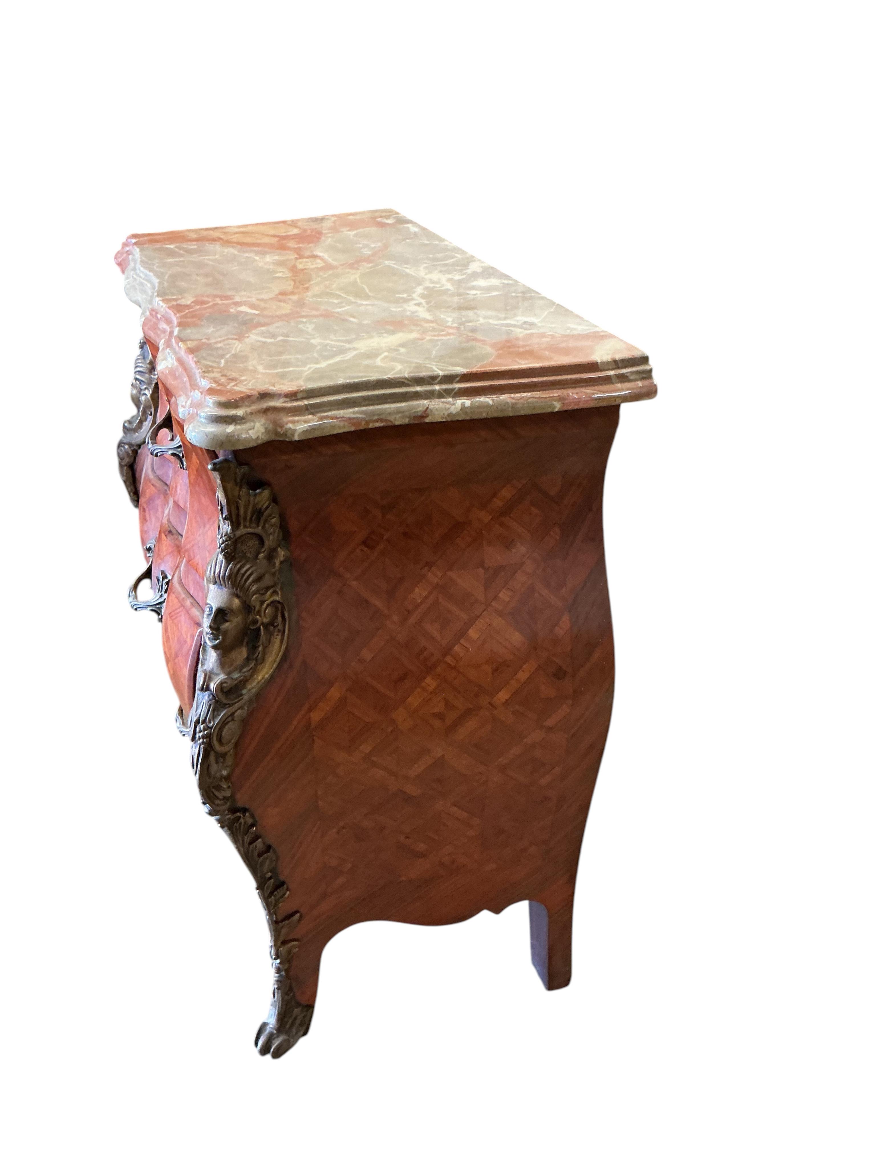 A pair of French transitional style bombe gilt metal mounted onyx top three drawer bedside chests, width 61cm, depth 33cm, height 71cm
